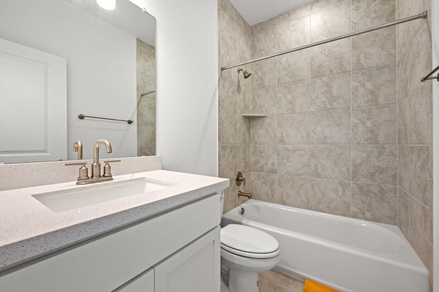 Tiled tub surround and a modern stone-countertop vanity define this clean secondary bathroom.