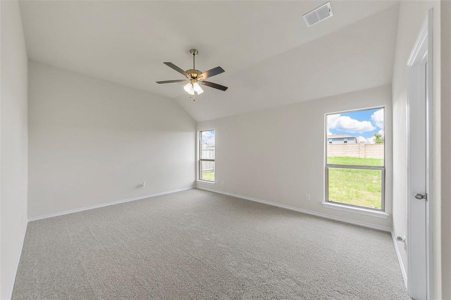 Carpeted empty room with baseboards, lofted ceiling, and ceiling fan Carpeted empty room with baseboards, lofted ceiling, and ceiling fan