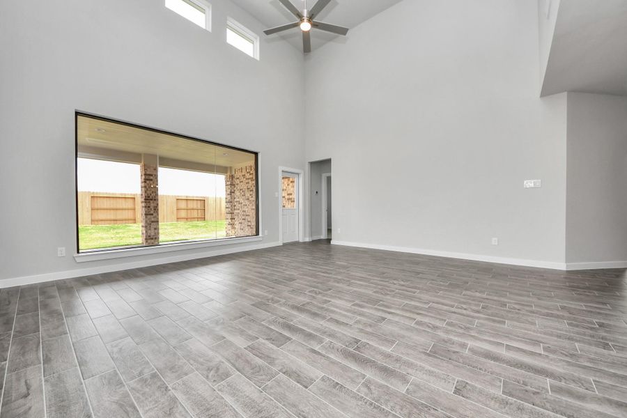 Welcome family and guests to your charming living room! With its high ceilings, recessed lighting, ceiling fan, custom paint, beautiful flooring, and large windows that let in abundant natural light, this room is perfect for gatherings.