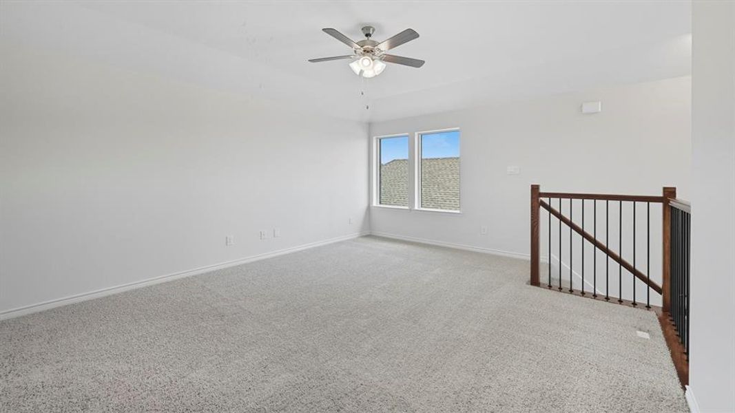 Carpeted empty room with baseboards and a ceiling fan Carpeted empty room with baseboards and a ceiling fan