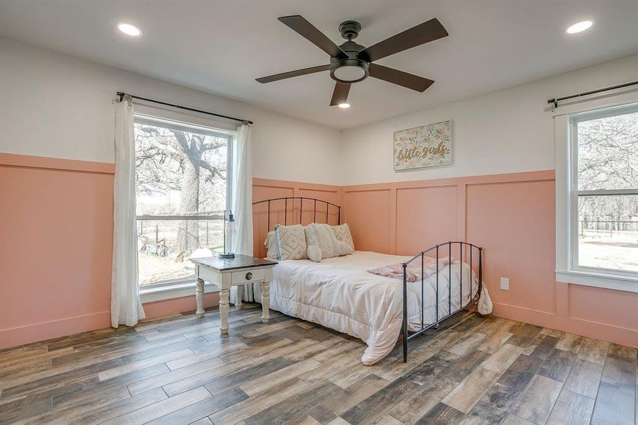 Bedroom with wainscoting, a decorative wall, recessed lighting, wood finished floors, and a ceiling fan