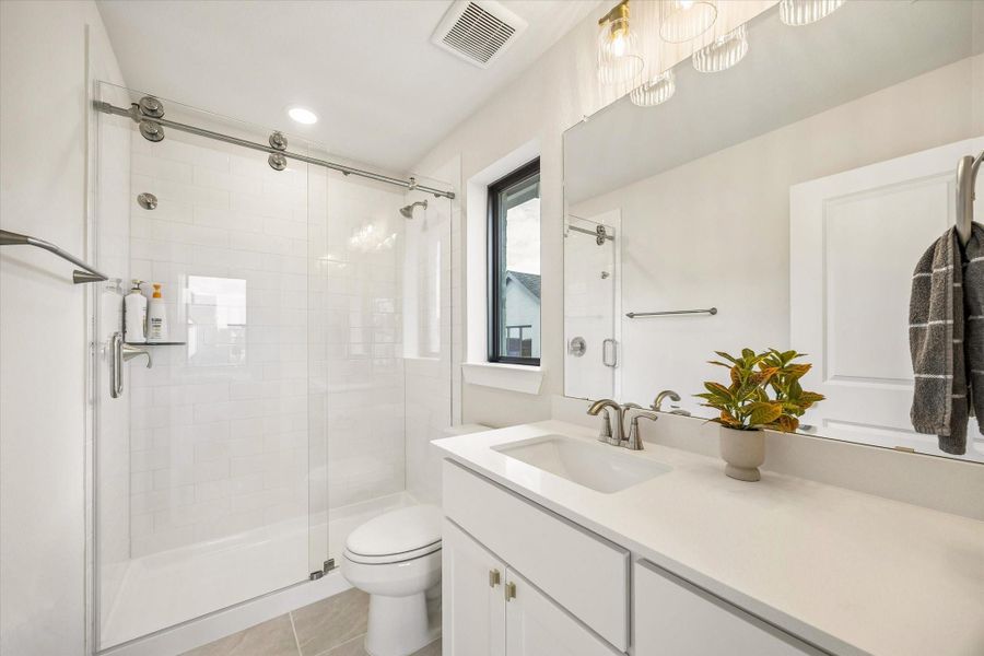 ANOTHER SECONDARY BATH OFFERS A WALK-IN SHOWER WITH FRAMELESS GLASS, SUBWAY TILE, QUARTZ COUNTERTOPS, AND A LARGE MIRROR. ANOTHER SECONDARY BATH OFFERS A WALK-IN SHOWER WITH FRAMELESS GLASS, SUBWAY TILE, QUARTZ COUNTERTOPS, AND A LARGE MIRROR.