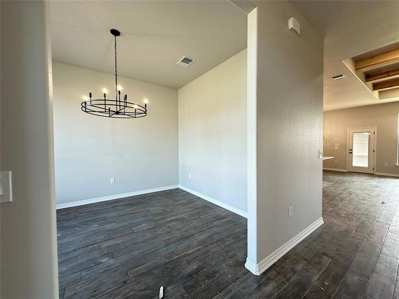 Unfurnished dining area with dark wood-style flooring and a chandelier Unfurnished dining area with dark wood-style flooring and a chandelier