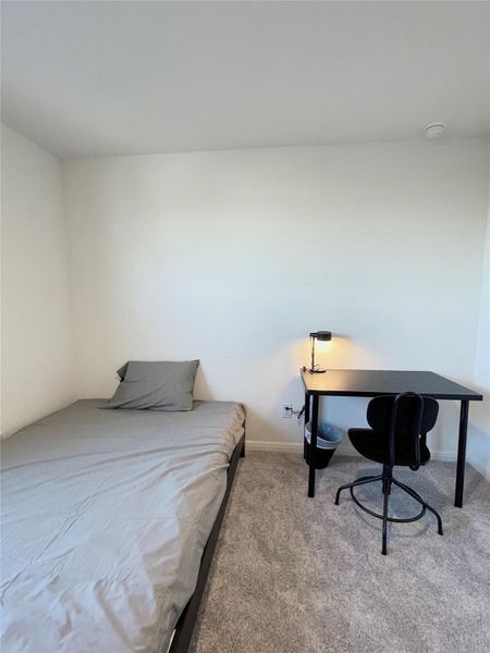 Carpeted bedroom with baseboards and an office area