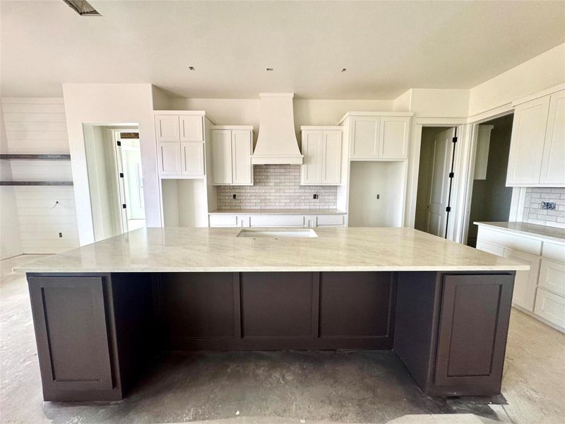 A spacious kitchen island provides ample counter space, complemented by crisp white cabinetry and modern subway tile.
