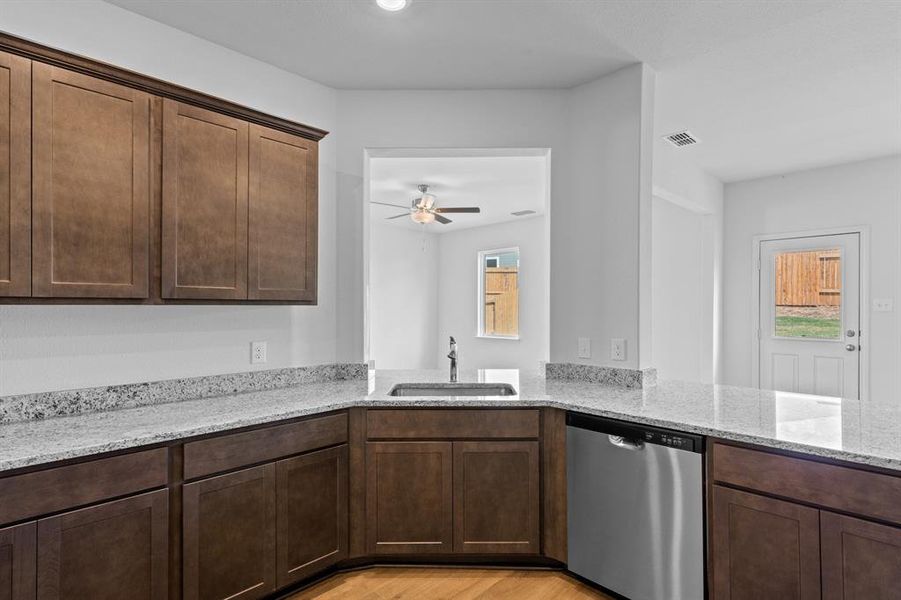 Kitchen featuring dishwasher, light stone countertops, and healthy amount of natural light Kitchen featuring dishwasher, light stone countertops, and healthy amount of natural light