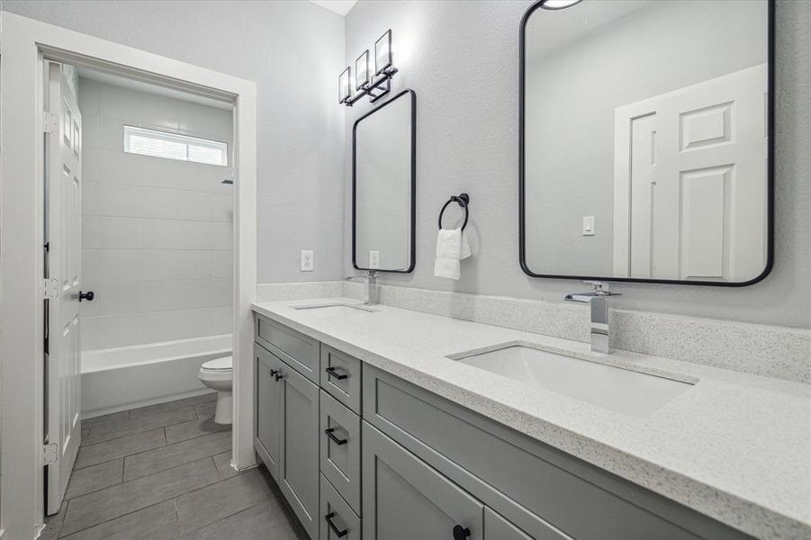 Guest bath with dual vanities, tub/ shower combowith tile surround.