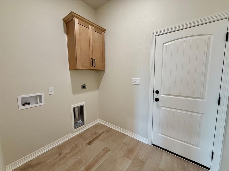 Washroom featuring hookup for an electric dryer, light wood finished floors, washer hookup, and cabinet space