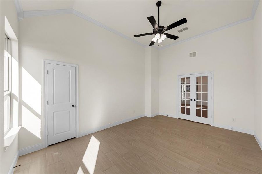 Spare room featuring crown molding, french doors, ceiling fan, vaulted ceiling, and light wood finished floors Spare room featuring crown molding, french doors, ceiling fan, vaulted ceiling, and light wood finished floors
