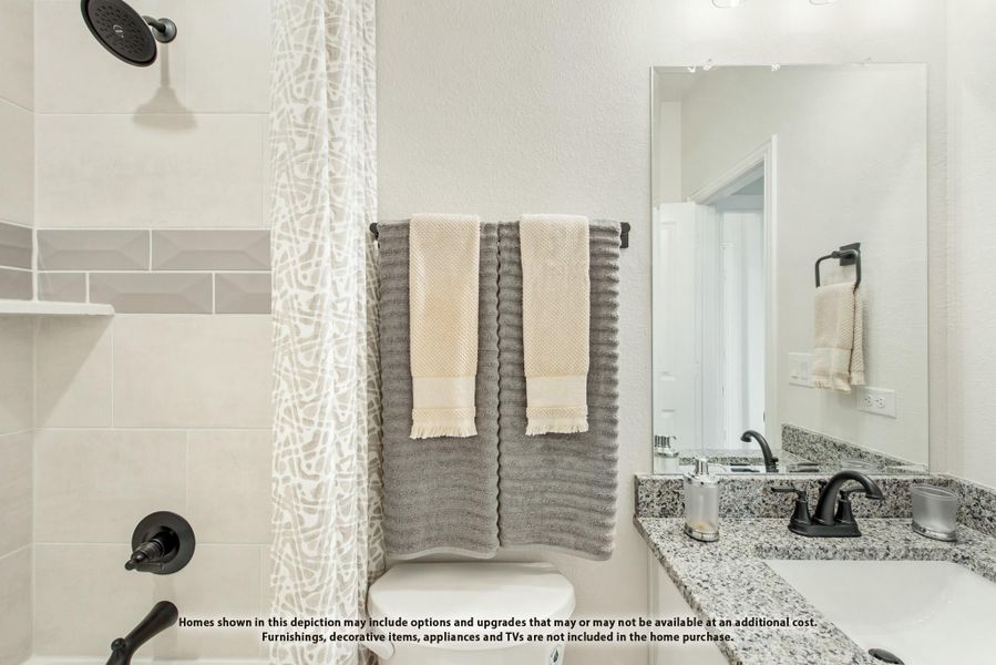 Bathroom with granite countertop, black fixtures, tiled shower with curtain, and large mirror above sink Bathroom with granite countertop, black fixtures, tiled shower with curtain, and large mirror above sink