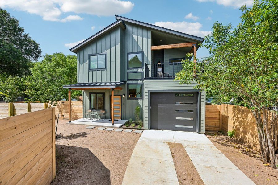 Modern green-sided home with a balcony, garage, and charming front porch. Modern green-sided home with a balcony, garage, and charming front porch.