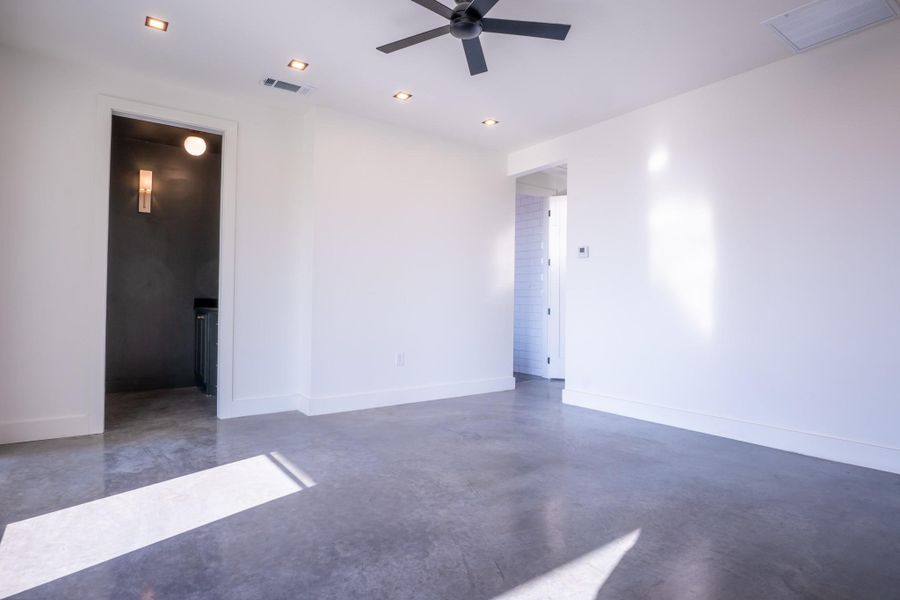 Empty room with finished concrete flooring and a ceiling fan