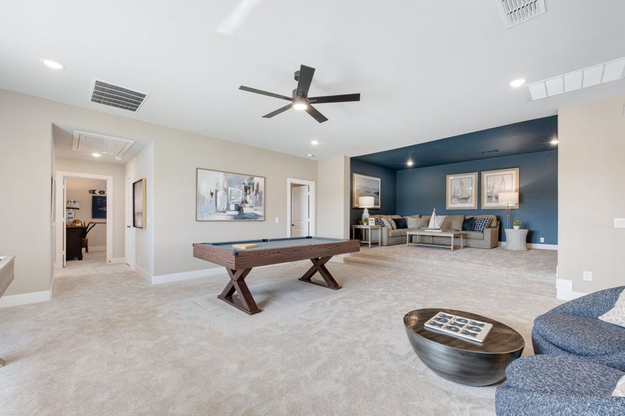 Large bonus room with pool table, seating area, blue accent wall, and ceiling fan over carpet flooring