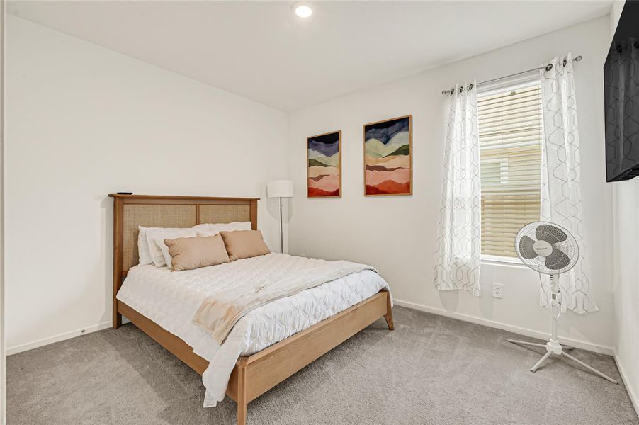 Cozy bedroom with a comfortable bed, soft carpeting, and natural light from a window adorned with elegant curtains. Cozy bedroom with a comfortable bed, soft carpeting, and natural light from a window adorned with elegant curtains.