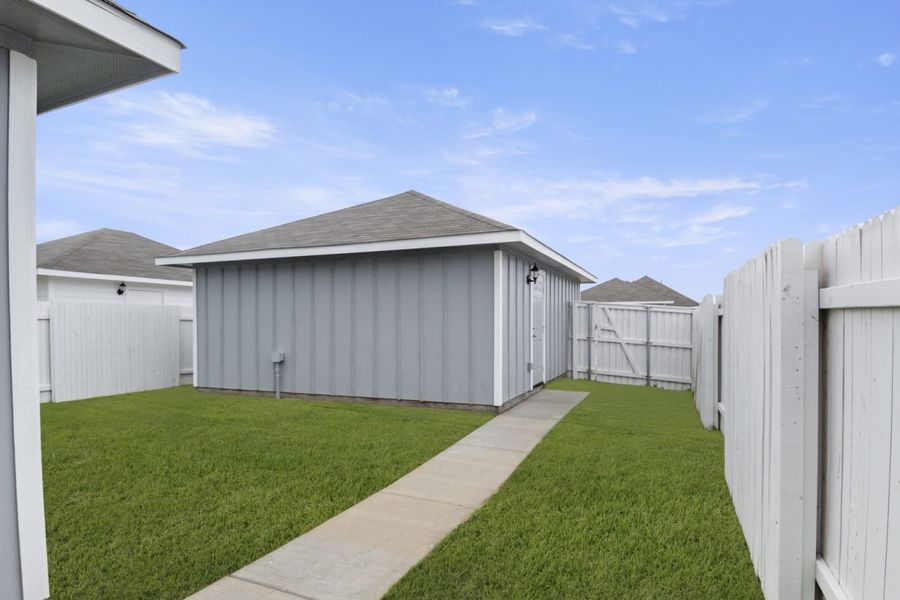 Image of grey home backyard with a white fence