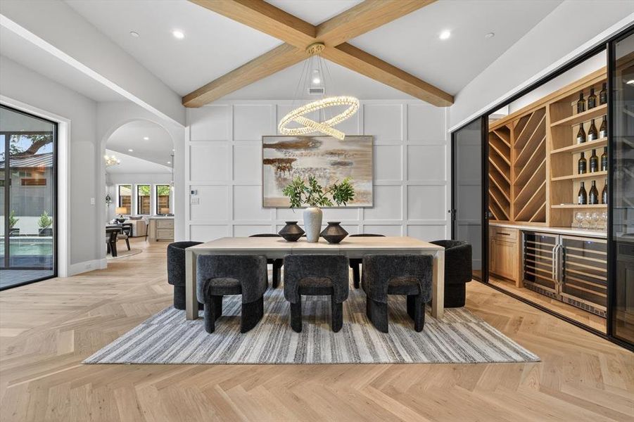 Vaulted ceiling featuring exposed wood beams, herringbone wood-finish flooring, and a built-in wine storage system with integrated coolers Vaulted ceiling featuring exposed wood beams, herringbone wood-finish flooring, and a built-in wine storage system with integrated coolers