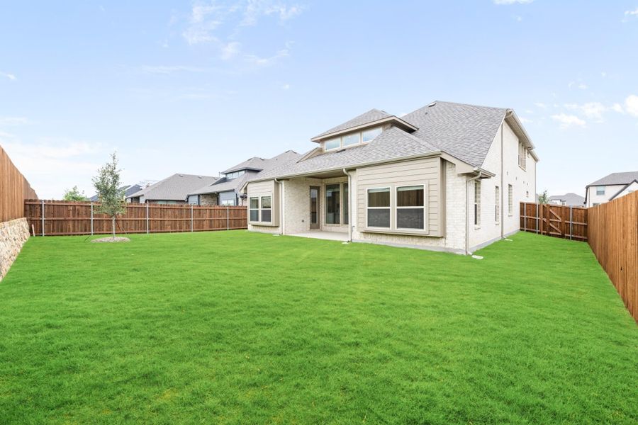 Rear view of two-story brick home with large fenced backyard and covered patio Rear view of two-story brick home with large fenced backyard and covered patio