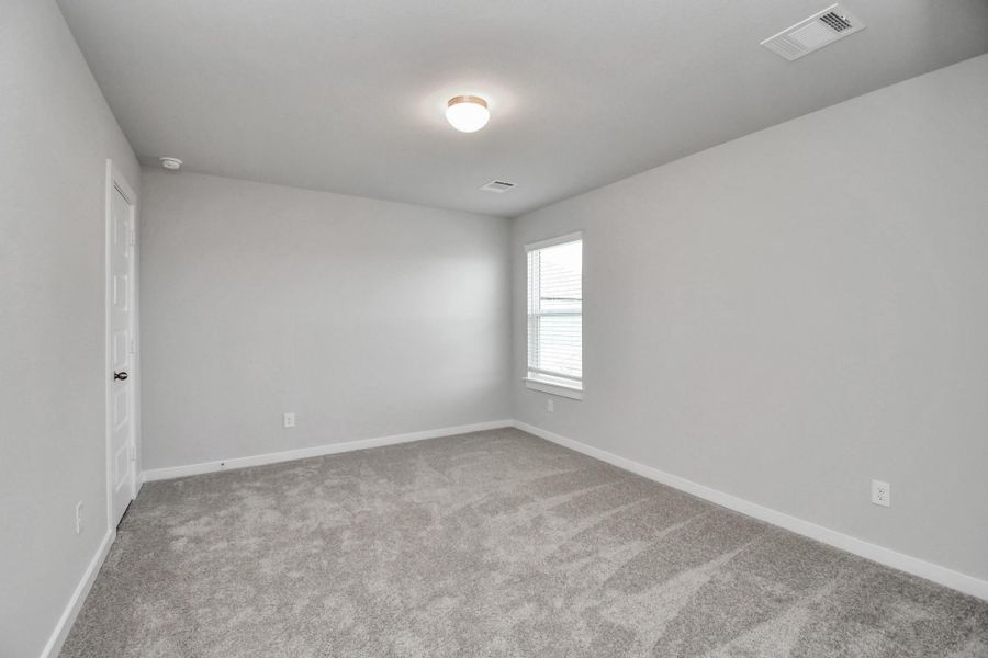 Secondary bedroom features plush carpeting, large windows that let in plenty of natural light, bright paint, and spacious closets.