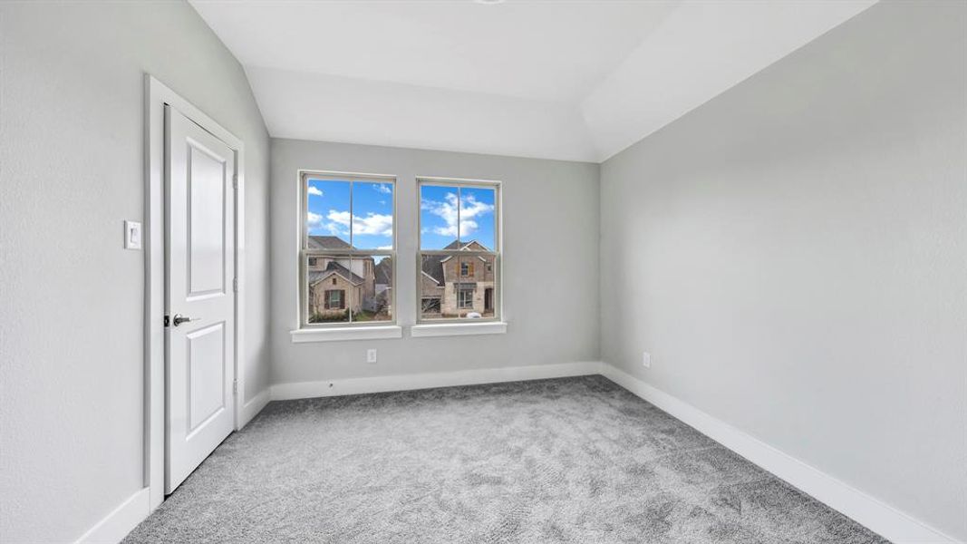 Empty room featuring light colored carpet and vaulted ceiling