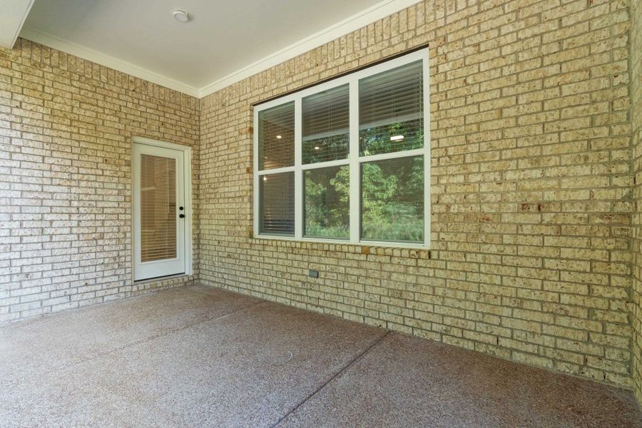 Covered patio with brick exterior, large picture window, and direct access door