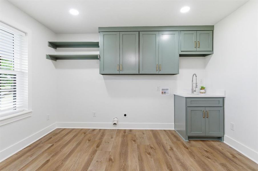 Utility space featuring light wood-look flooring, white walls, and a window with blinds Utility space featuring light wood-look flooring, white walls, and a window with blinds