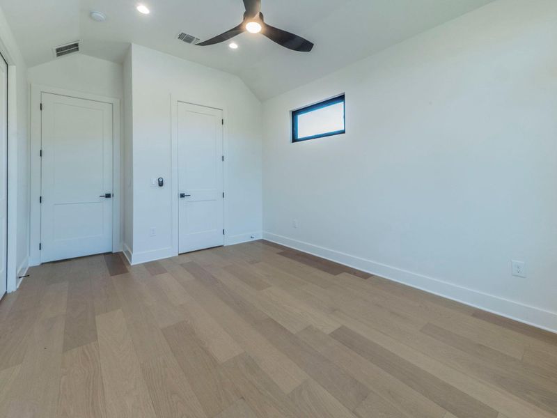 Unfurnished bedroom with vaulted ceiling, light wood finished floors, a ceiling fan, and recessed lighting Unfurnished bedroom with vaulted ceiling, light wood finished floors, a ceiling fan, and recessed lighting