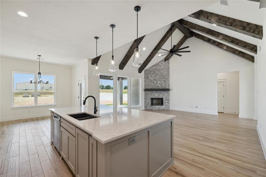 Kitchen featuring a wealth of natural light, light stone counters, light wood-type flooring, and a stone fireplace