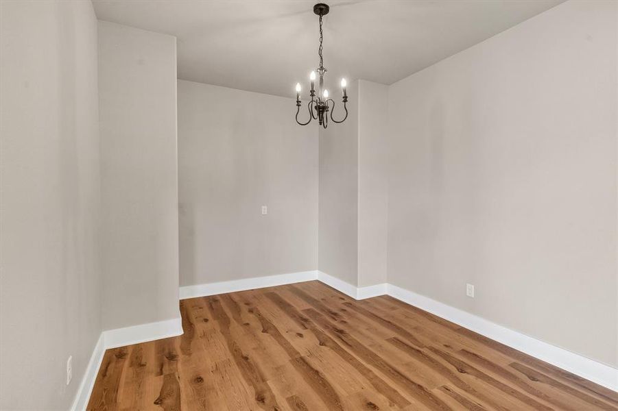 Unfurnished dining area featuring wood finished floors and a chandelier