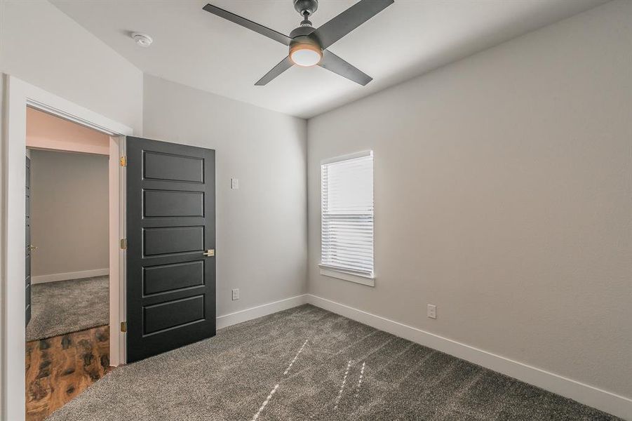 Carpeted empty room featuring ceiling fan