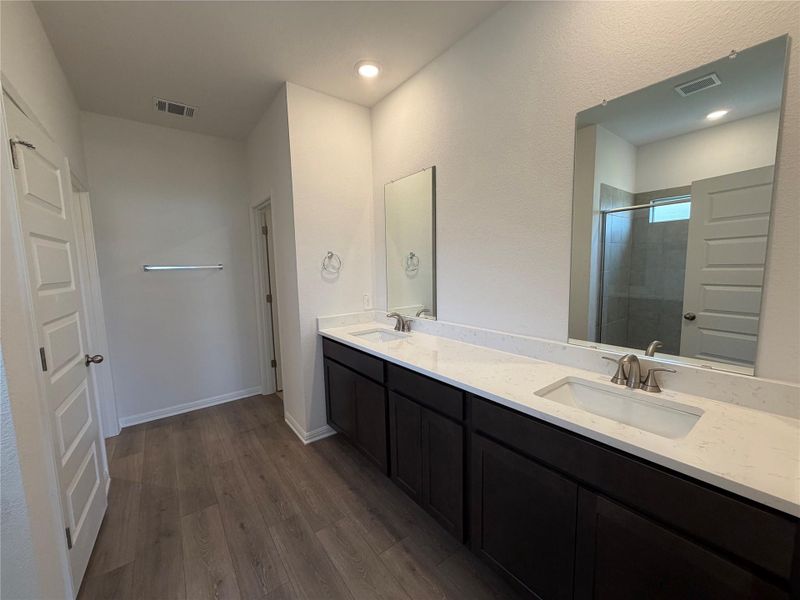 Bathroom with double vanity, dark wood-style floors, a shower stall, and recessed lighting