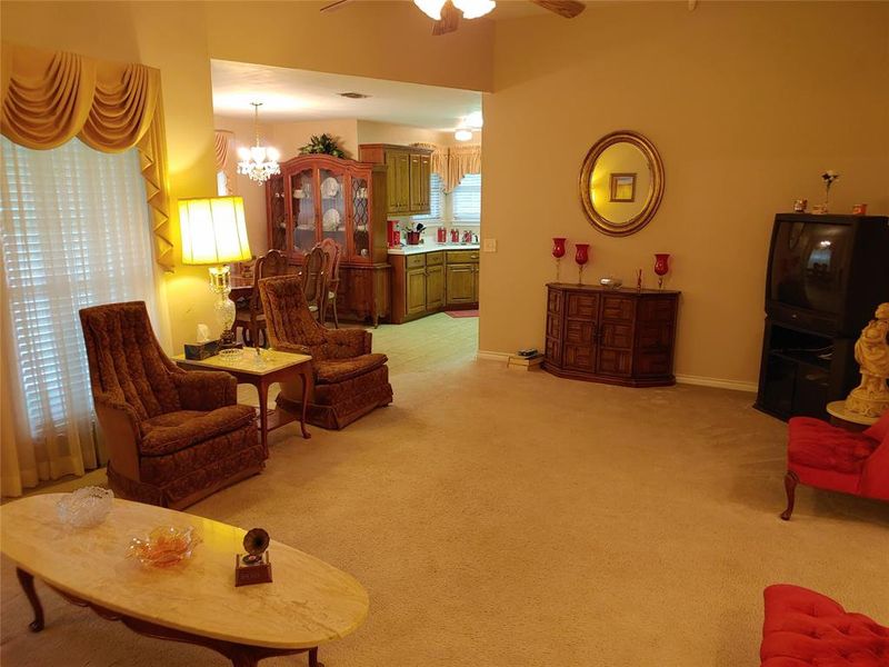Carpeted living area with vaulted ceilings and a ceiling fan