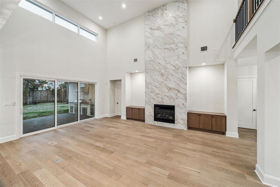 Living room features high ceilings, gas fireplace with tiled bumpout floor to ceiling, massive sliding back door