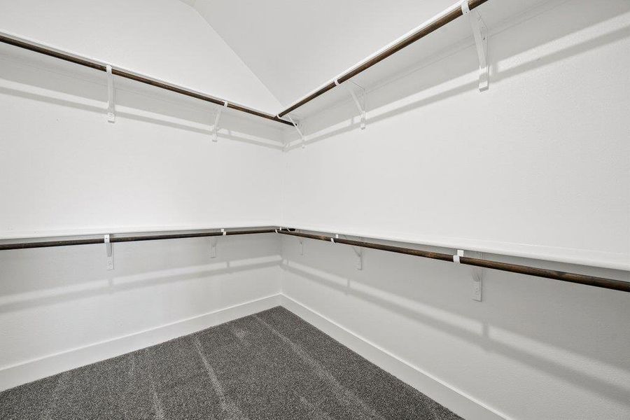Walk in closet with dark colored carpet and lofted ceiling Walk in closet with dark colored carpet and lofted ceiling