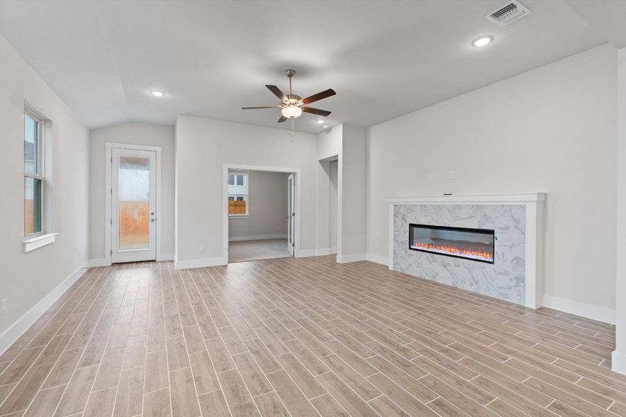A well-lit living area features an elegant fireplace and wood-look tile flooring. A well-lit living area features an elegant fireplace and wood-look tile flooring.
