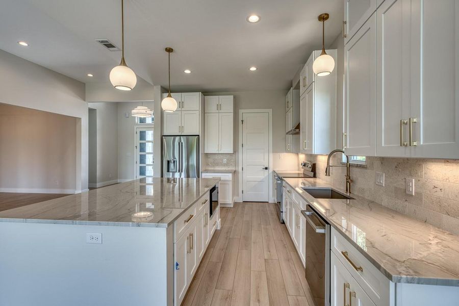 Culinary dreams come alive in this kitchen, featuring an oversized island, stainless steel appliances, and elegant recessed lighting.