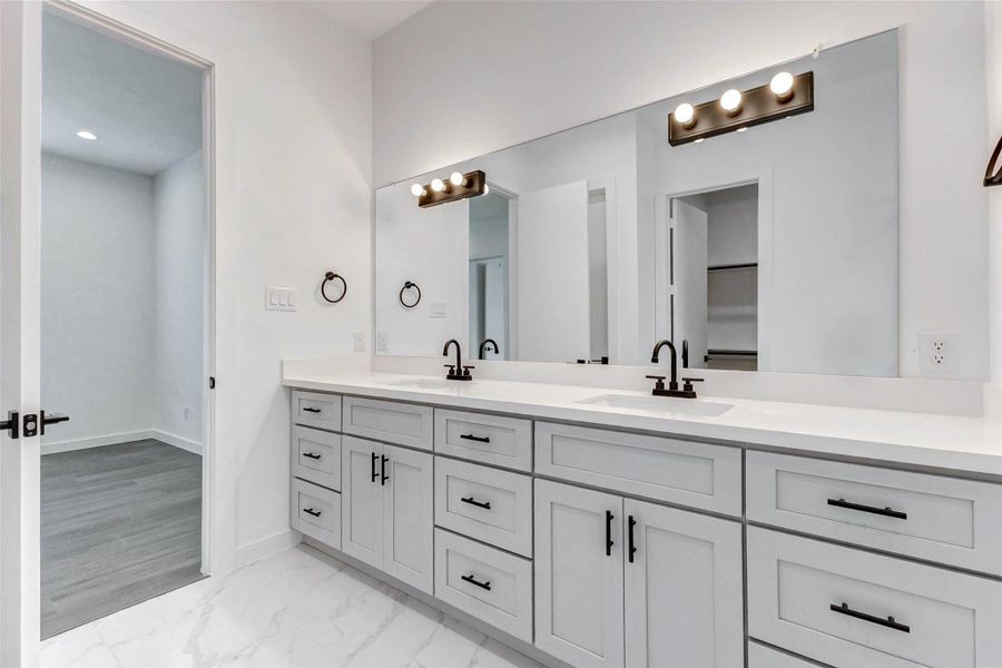 Timeless meets modern in this en-suite bath with double sinks, generous counter space, and an abundance of soft natural light. Perfect for peaceful mornings and functional routines alike. Timeless meets modern in this en-suite bath with double sinks, generous counter space, and an abundance of soft natural light. Perfect for peaceful mornings and functional routines alike.