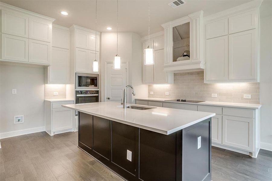 Kitchen with wood-type flooring, sink, an island with sink, appliances with stainless steel finishes, and white cabinets