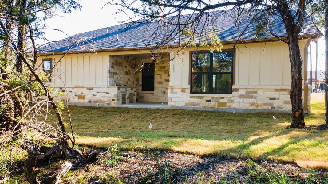 View of front of house featuring a front lawn, a shingled roof, board and batten siding, and stone siding
