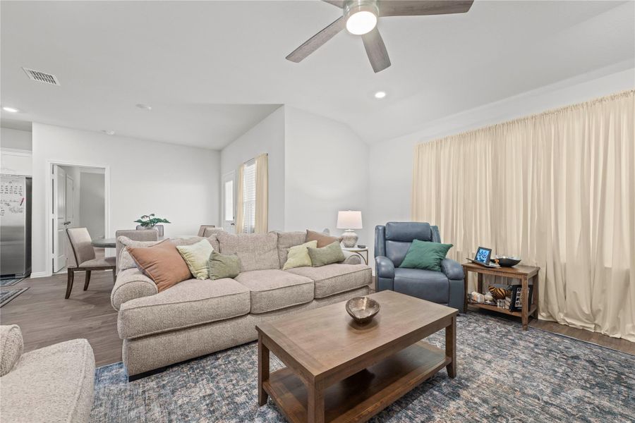An inviting living area features a ceiling fan, recessed lighting, and durable hardwood flooring.