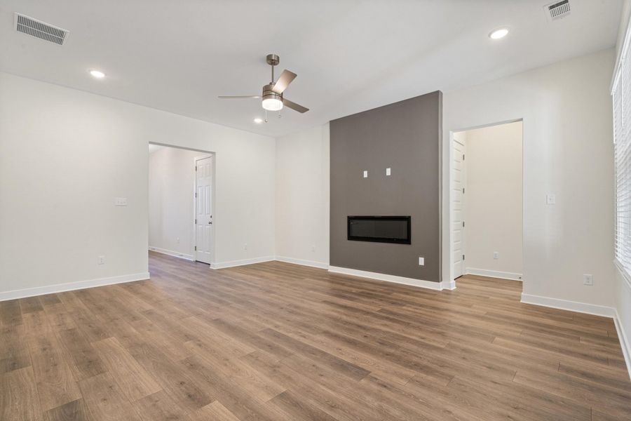 Unfurnished living room featuring a ceiling fan, a glass covered fireplace, light wood-style floors, and recessed lighting