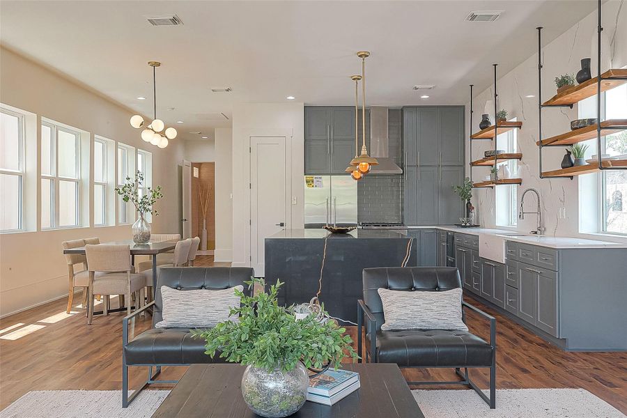 This is a modern open-concept living space with a combined kitchen and dining area, featuring elegant dark cabinetry, floating wooden shelves, chic pendant lighting, and ample natural light from large windows. The hardwood floors add warmth to the space, which is accented by stylish, contemporary furnishings. This is a modern open-concept living space with a combined kitchen and dining area, featuring elegant dark cabinetry, floating wooden shelves, chic pendant lighting, and ample natural light from large windows. The hardwood floors add warmth to the space, which is accented by stylish, contemporary furnishings.