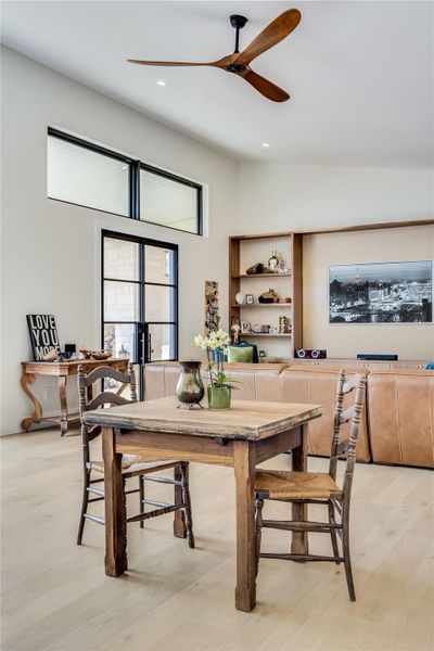 Dining area featuring light wood-type flooring, a ceiling fan, and a high ceiling