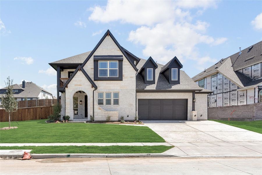 Two-story home with light stone exterior, dark trim accents, arched entry, and two-car garage with green front lawn. Two-story home with light stone exterior, dark trim accents, arched entry, and two-car garage with green front lawn.