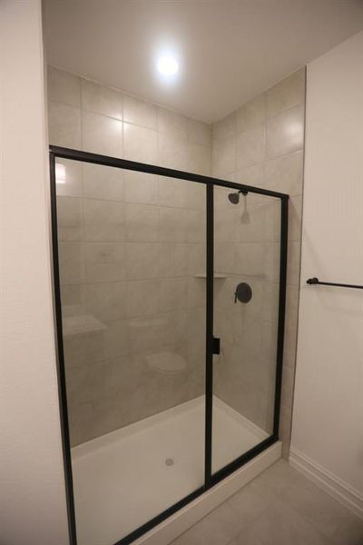Walk-in shower with clear glass enclosure and matte black frame