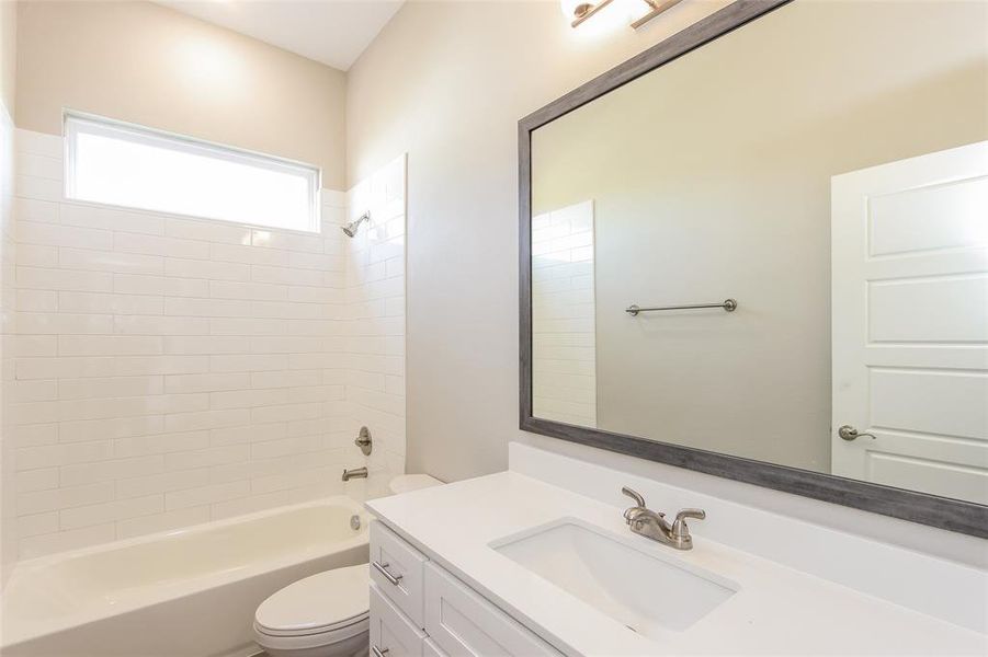 Full bathroom with tiled shower / bath, vanity, and toilet