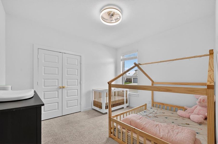 Bright room featuring a ceiling-mounted light fixture with fan, light-toned carpet flooring, white walls, and a window with blinds