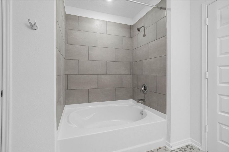 Relax and unwind in the primary bath, featuring a deep soaking tub surrounded by modern large-format tile.