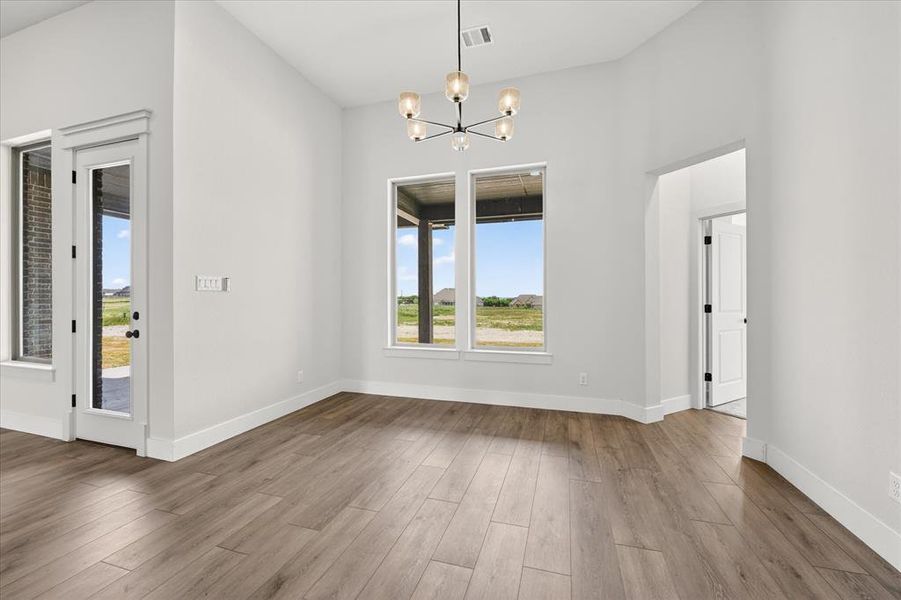 Unfurnished dining area with a chandelier, dark wood-type flooring, plenty of natural light, and a high ceiling