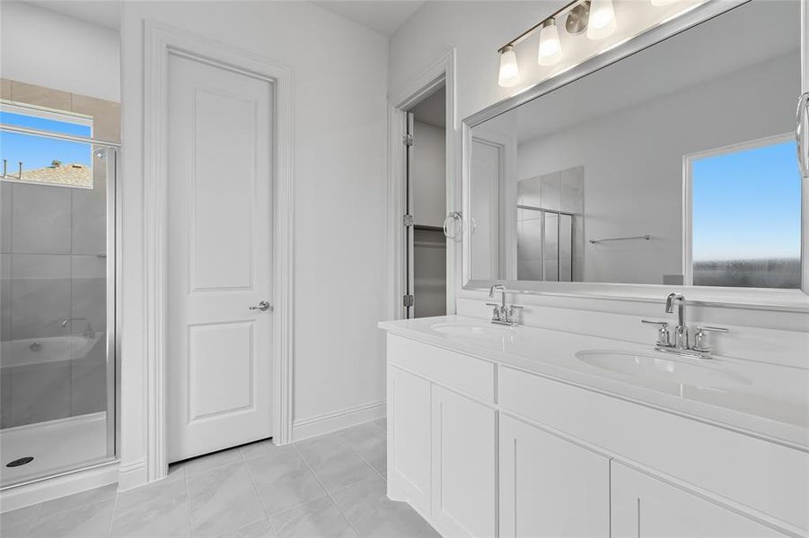 Bathroom featuring a shower stall, double vanity, a closet, and light tile patterned flooring