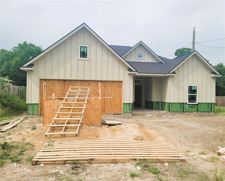 View of front of home featuring board and batten siding, roof with shingles, a garage, and driveway